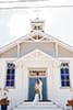 Bridal portraits in front of costal catholic church with boho bride in fringe dress and groom in light beige suit