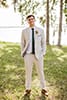 Light beige grooms suit with green tie and colorful, tropical boutonnières