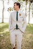 Light beige grooms suit with green tie and colorful, tropical boutonnières