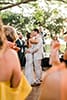 Boho bride in fringe dress parties with groom in light beige suit